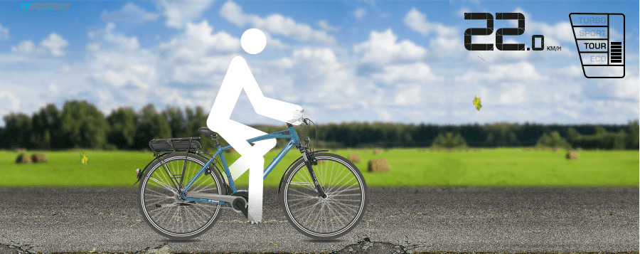 Eine Person fährt mit dem Fahrrad auf einer Straße. Im Hintergrund ist ein Feld zu sehen.