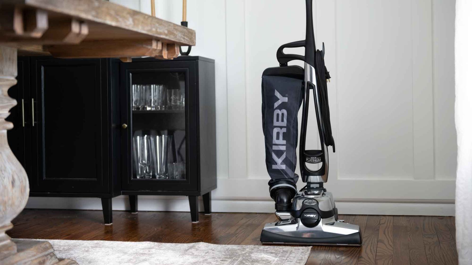 A kirby vacuum cleaner is sitting on the floor in a living room.