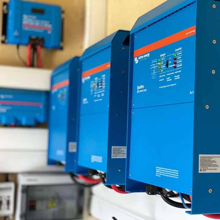 Blue solar energy inverters mounted on a wall, with visible wires and a smaller blue control panel.