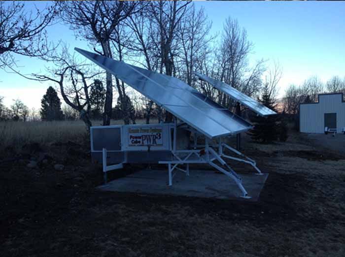 Solar panel array in a field, angled toward the sky, set on a concrete pad.