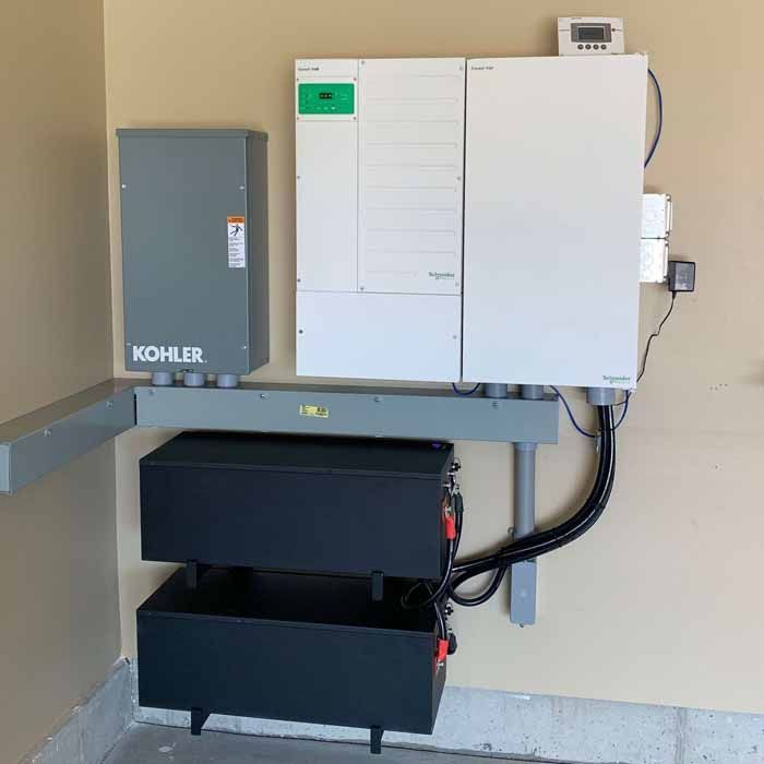 Solar power system with batteries, Kohler generator, and electrical components mounted on a wall.