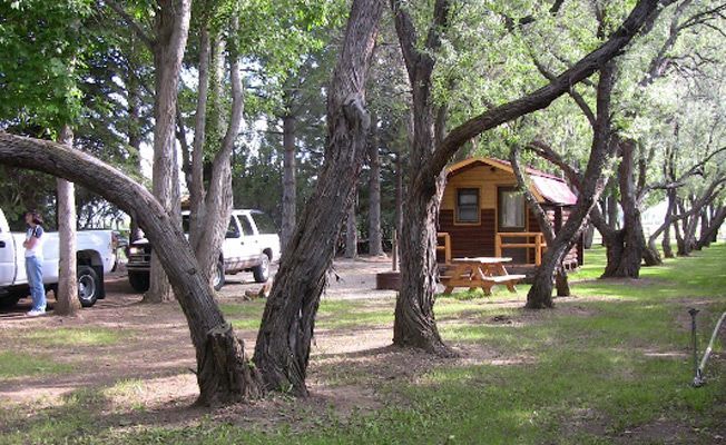 A truck is parked in front of a cabin in the woods
