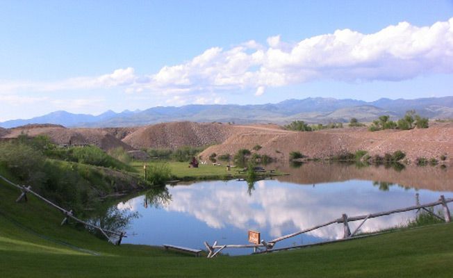 A large body of water with mountains in the background and trees in the foreground.