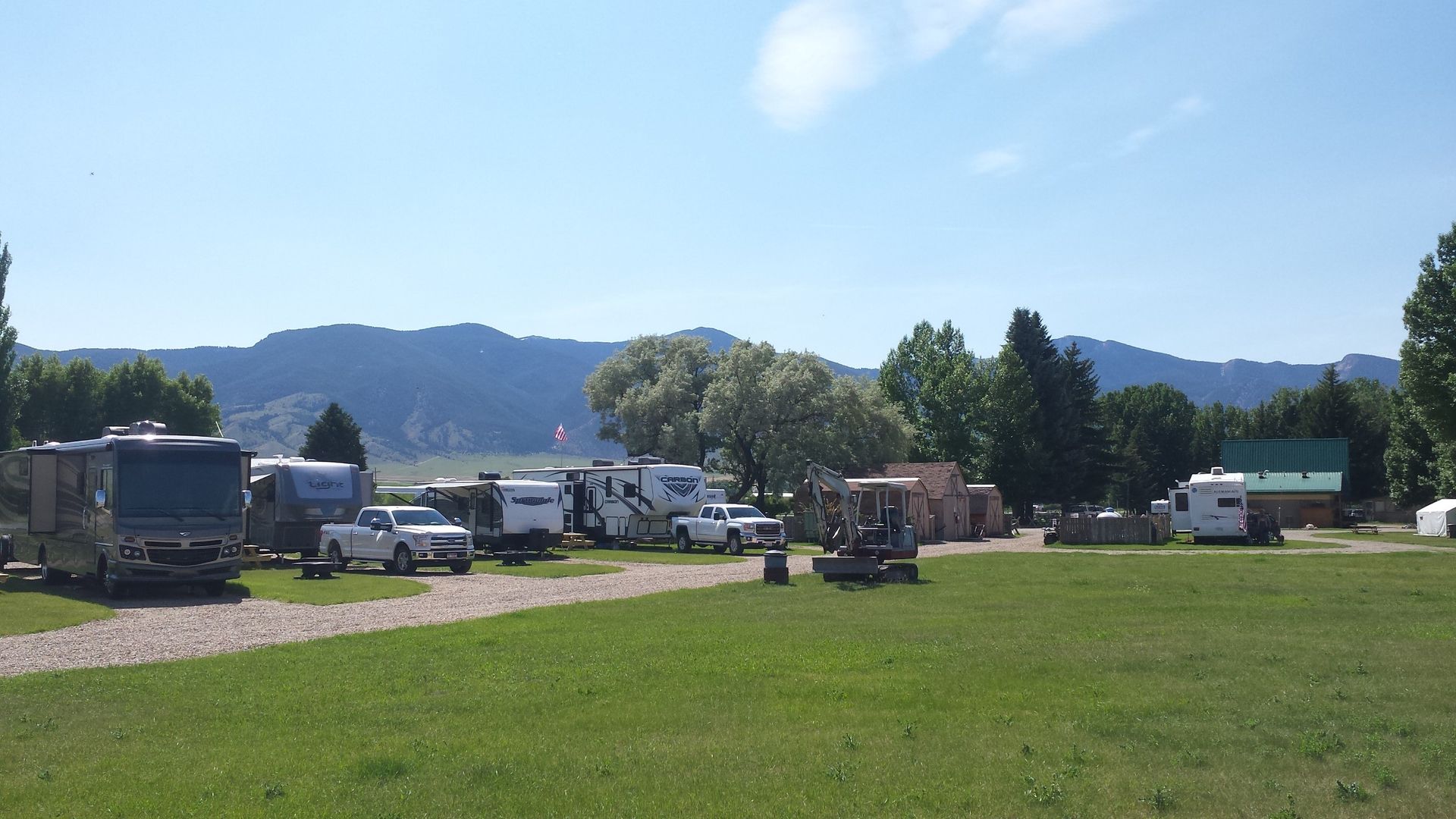 A row of rvs parked in a grassy field with mountains in the background