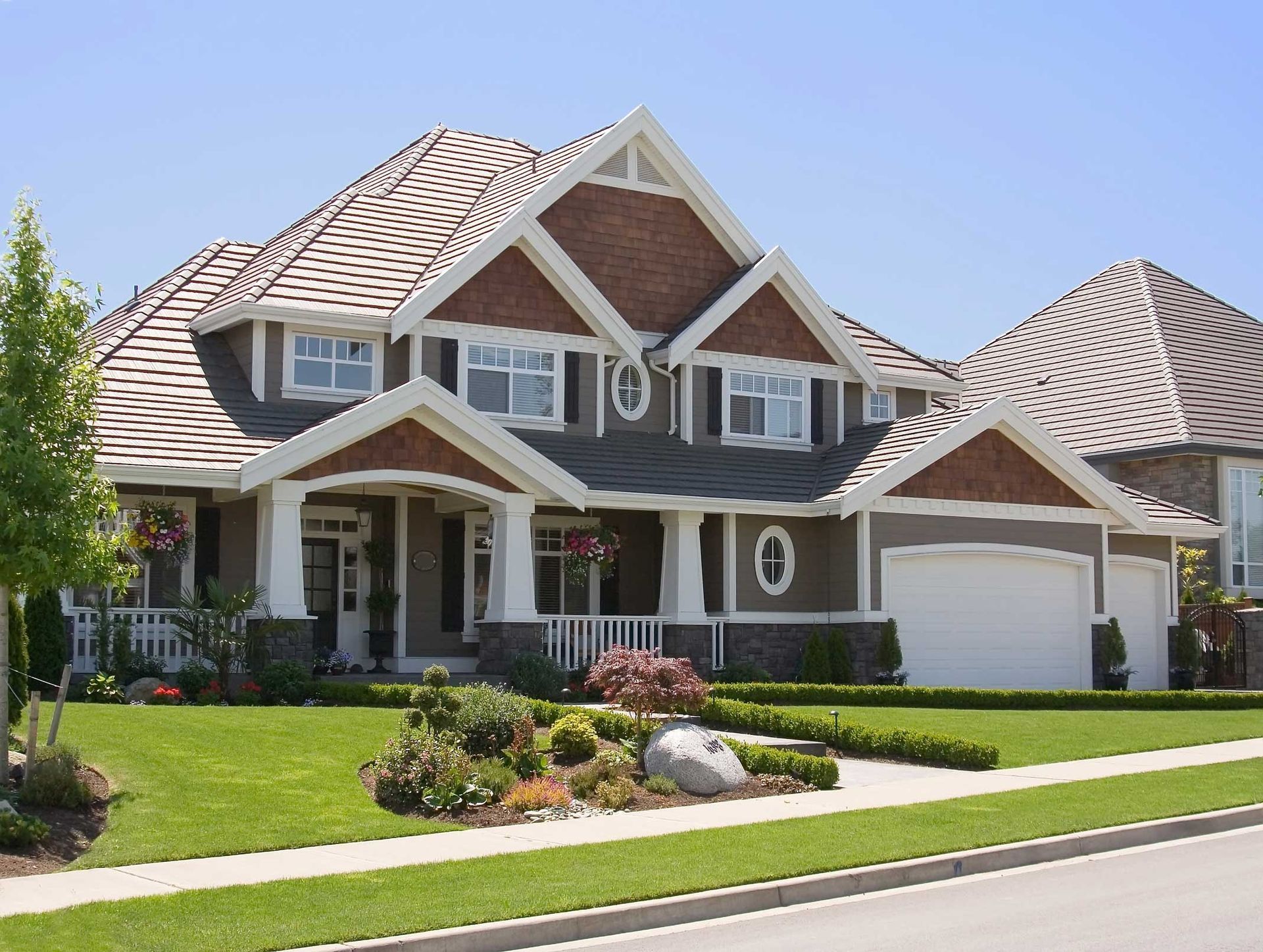 Large, brown house with white trim, green lawn, and blue sky.