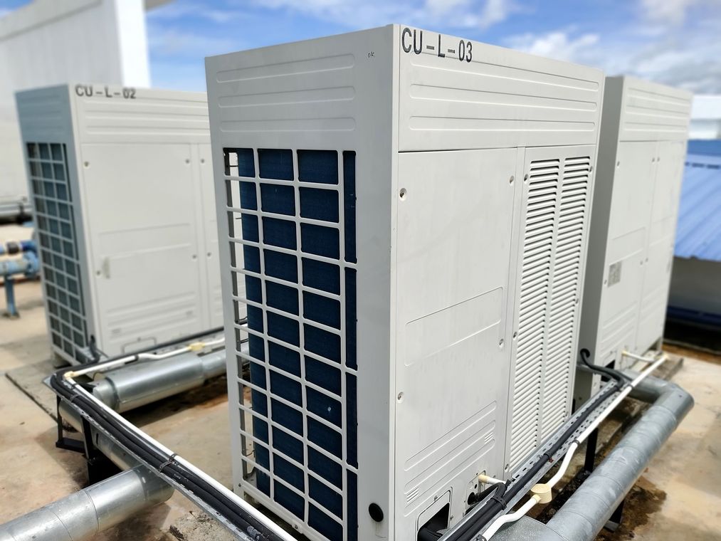 Three outdoor rooftop HVAC units with metal piping in a mechanical equipment area