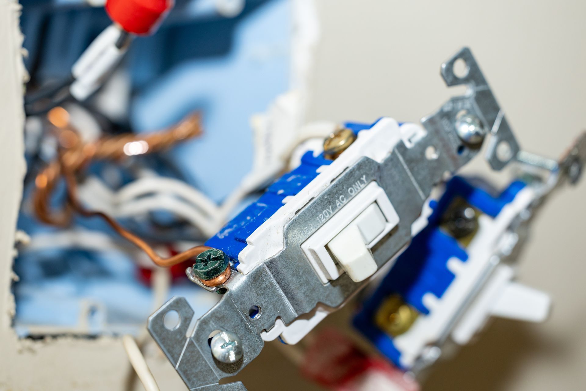 Close-up of an electrical switch being installed with exposed wiring and tools nearby