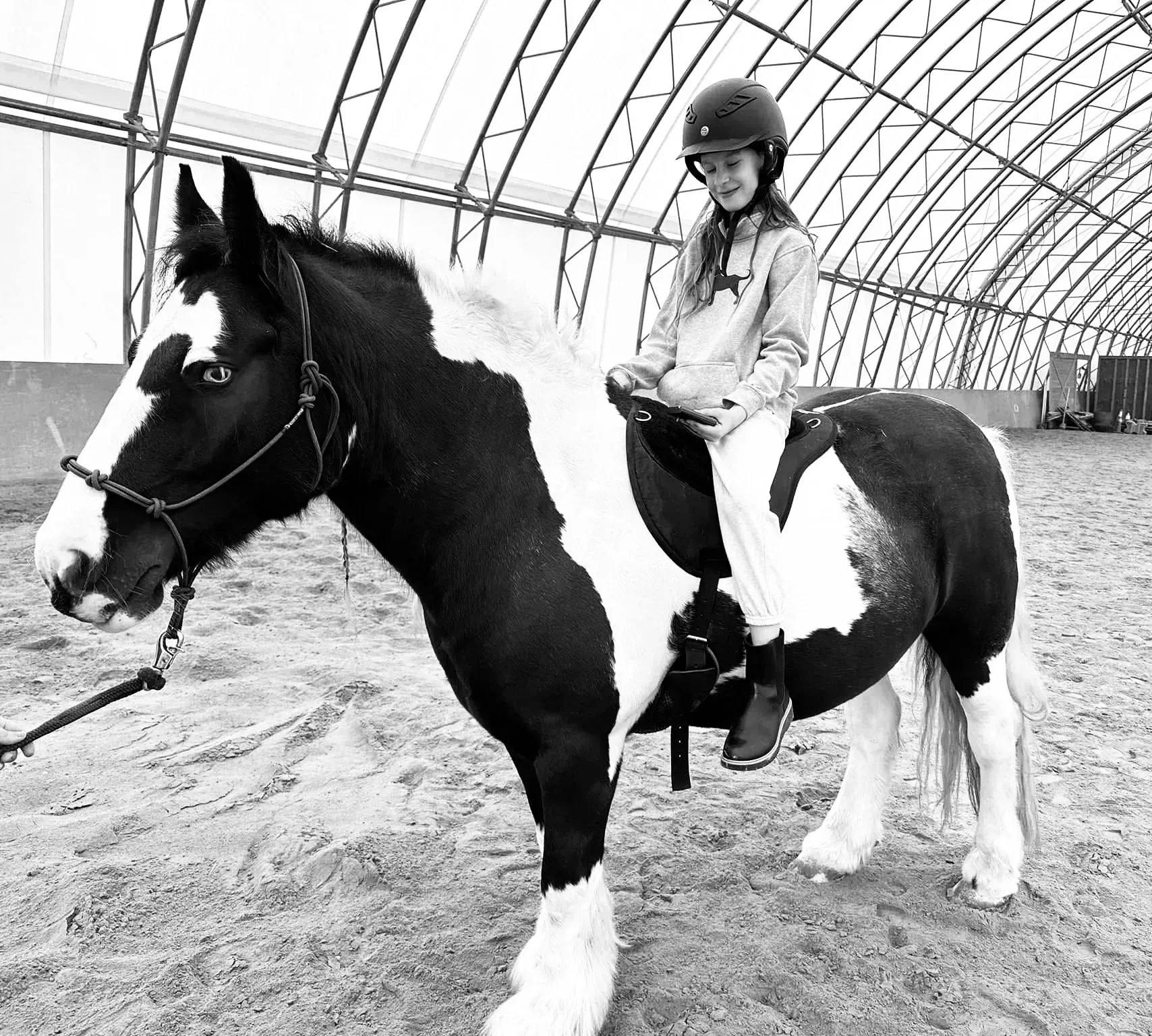 A girl is riding on the back of a black and white horse.