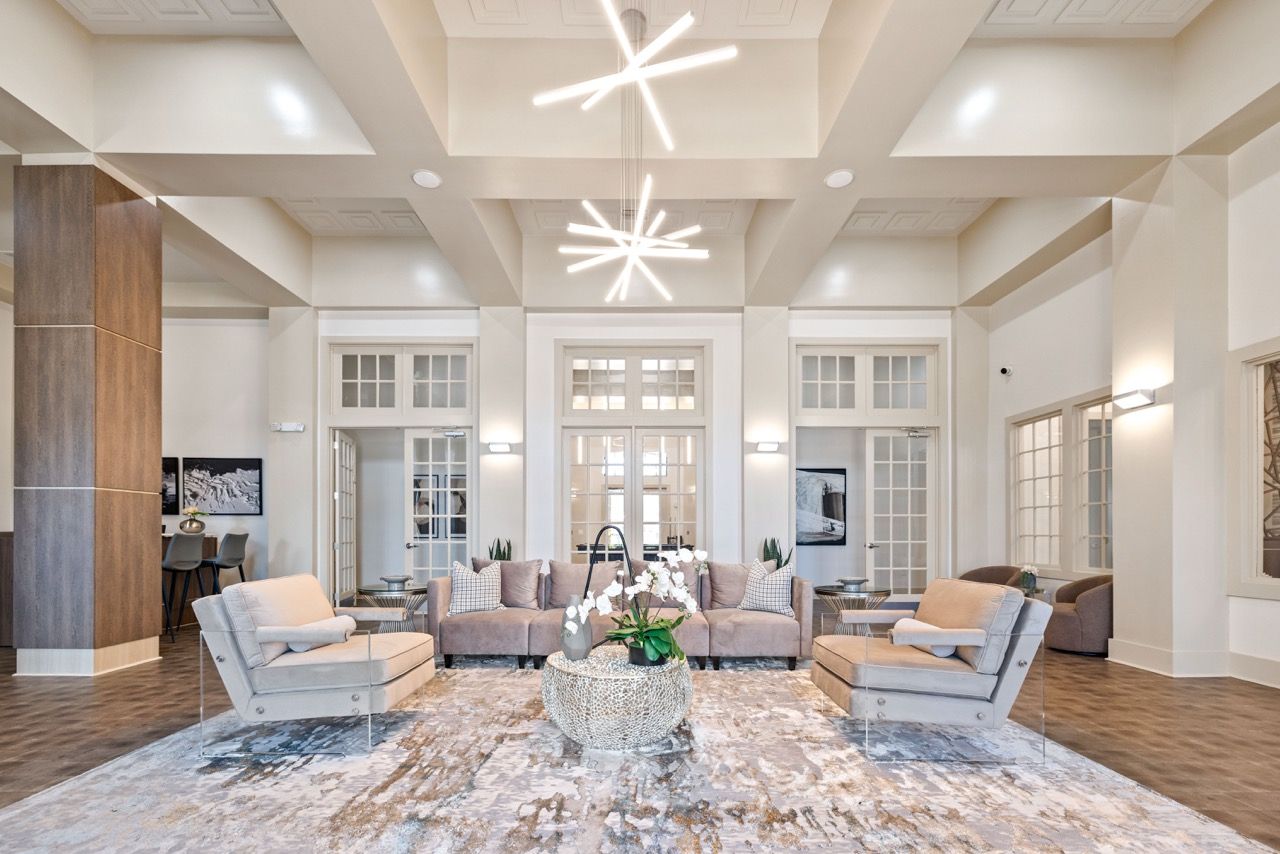 Bright, spacious residential lobby with beige seating, a central coffee table, and starburst light fixtures.