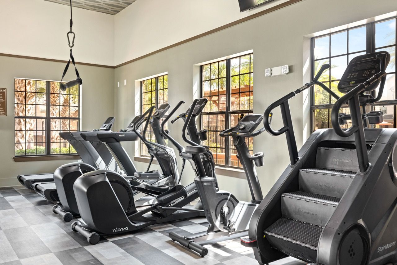 Indoor community gym with treadmills and elliptical machines by sunlit windows at The Hawthorne.