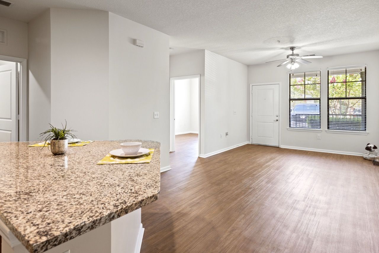 Open-concept living area with granite kitchen island, wood floors, and large windows atThe Hawthorne.