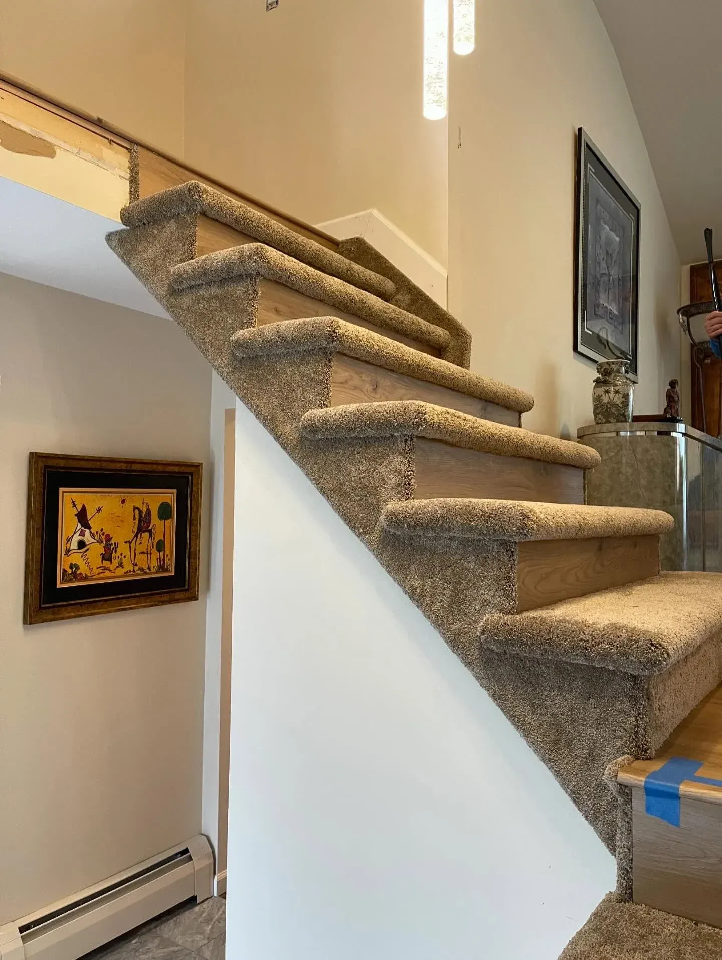 Carpeted indoor staircase with white walls and framed artwork on the landing.