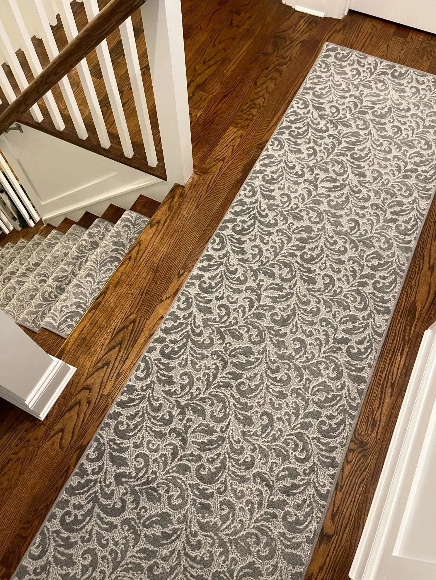 Runner rug in a wooden hallway beside a staircase and white doors