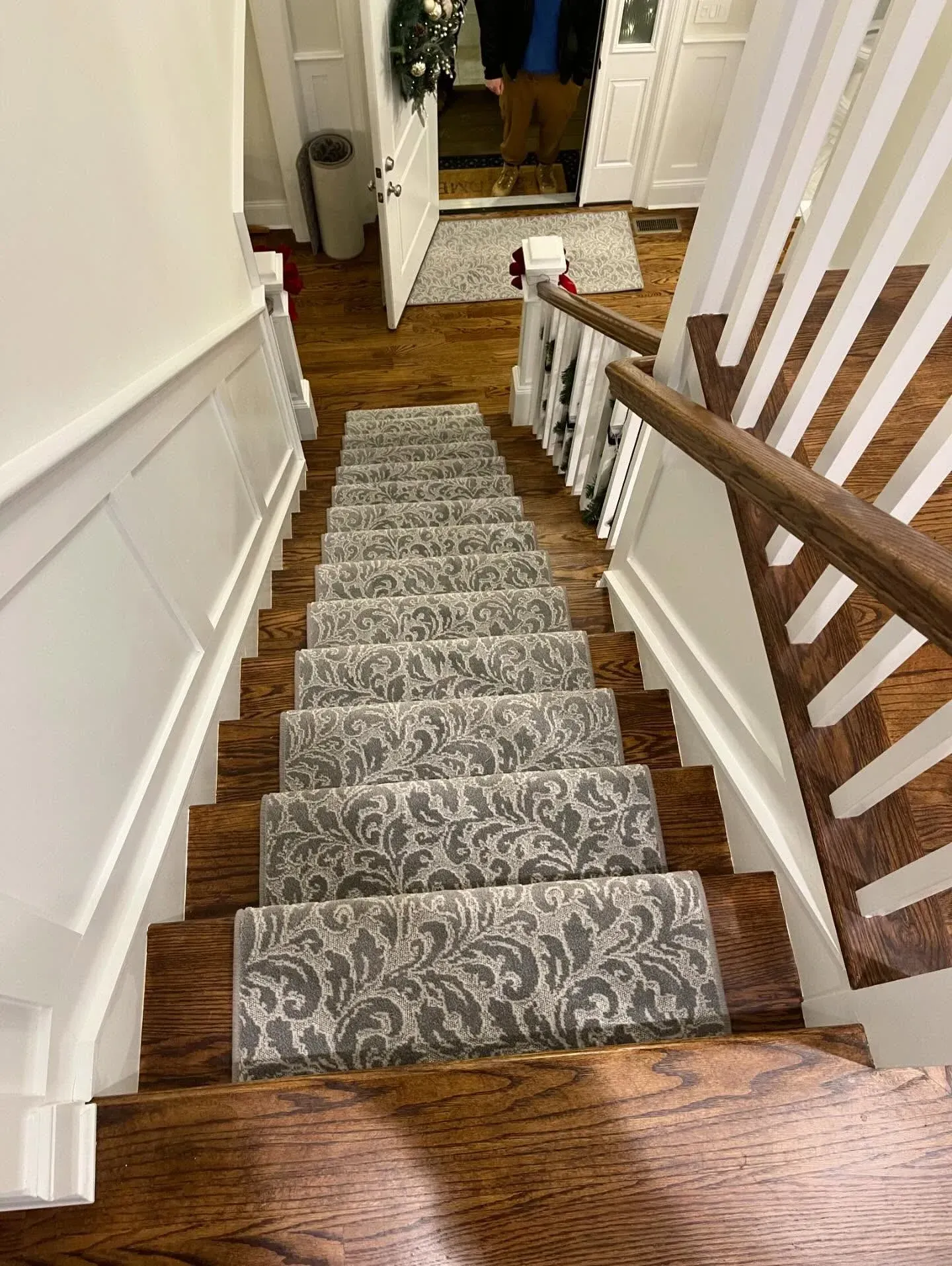 Staircase with gray patterned runner leading down to a hardwood floor hallway.