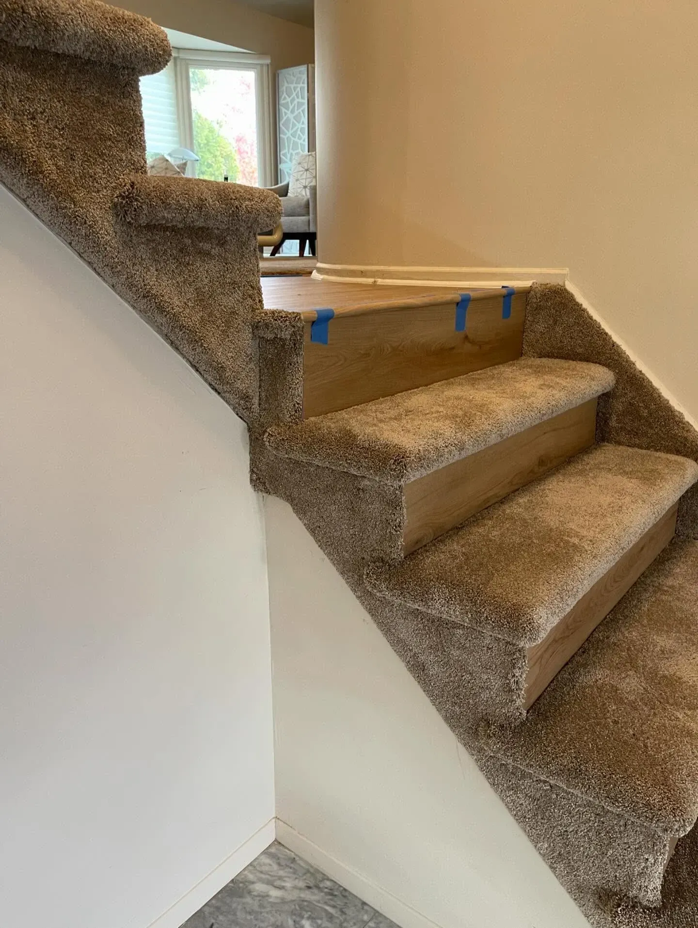 Carpeted staircase with a wooden board and blue tape blocking the landing area