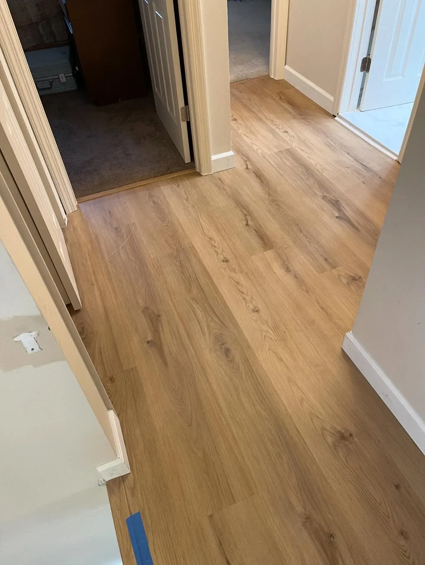 Light wood laminate hallway floor with doorways and white walls