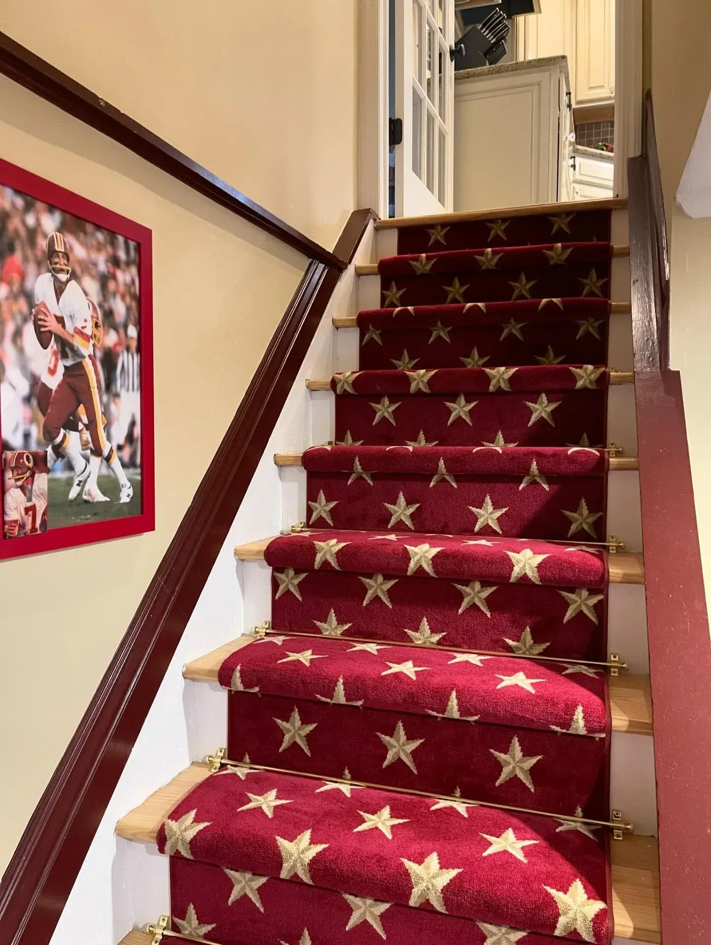 Red carpeted staircase with gold stars in a home hallway, viewed from the bottom up