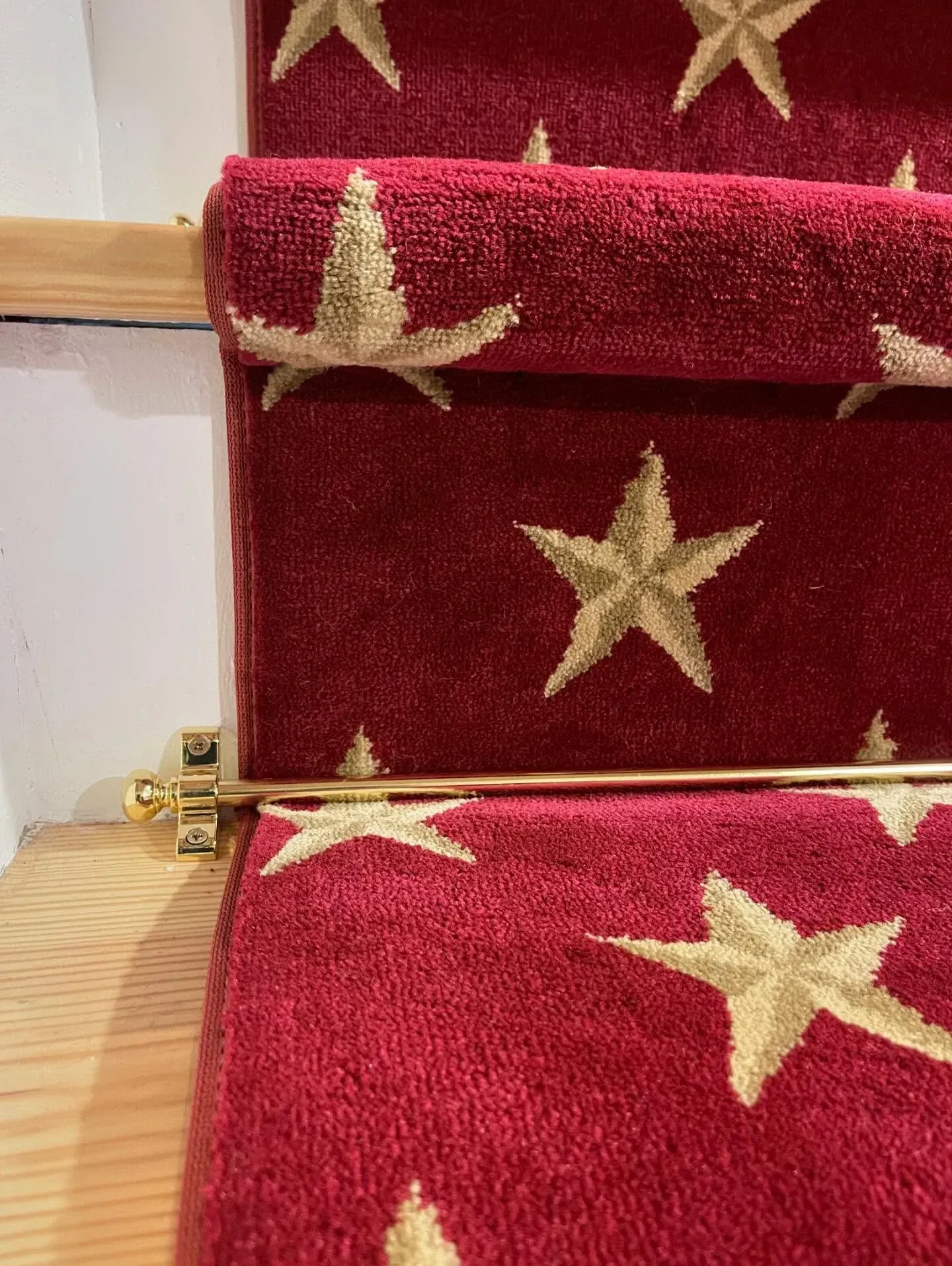 Red carpeted stairs with gold star patterns on a wooden floor.