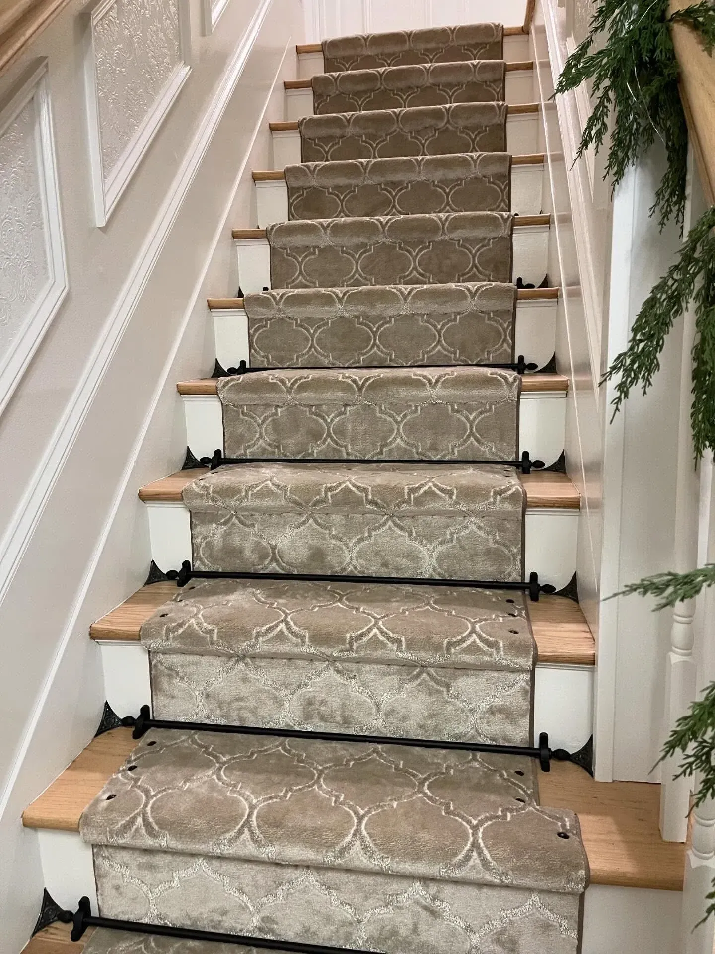 Carpeted indoor staircase with white trim, wooden steps, and a decorative runner rug