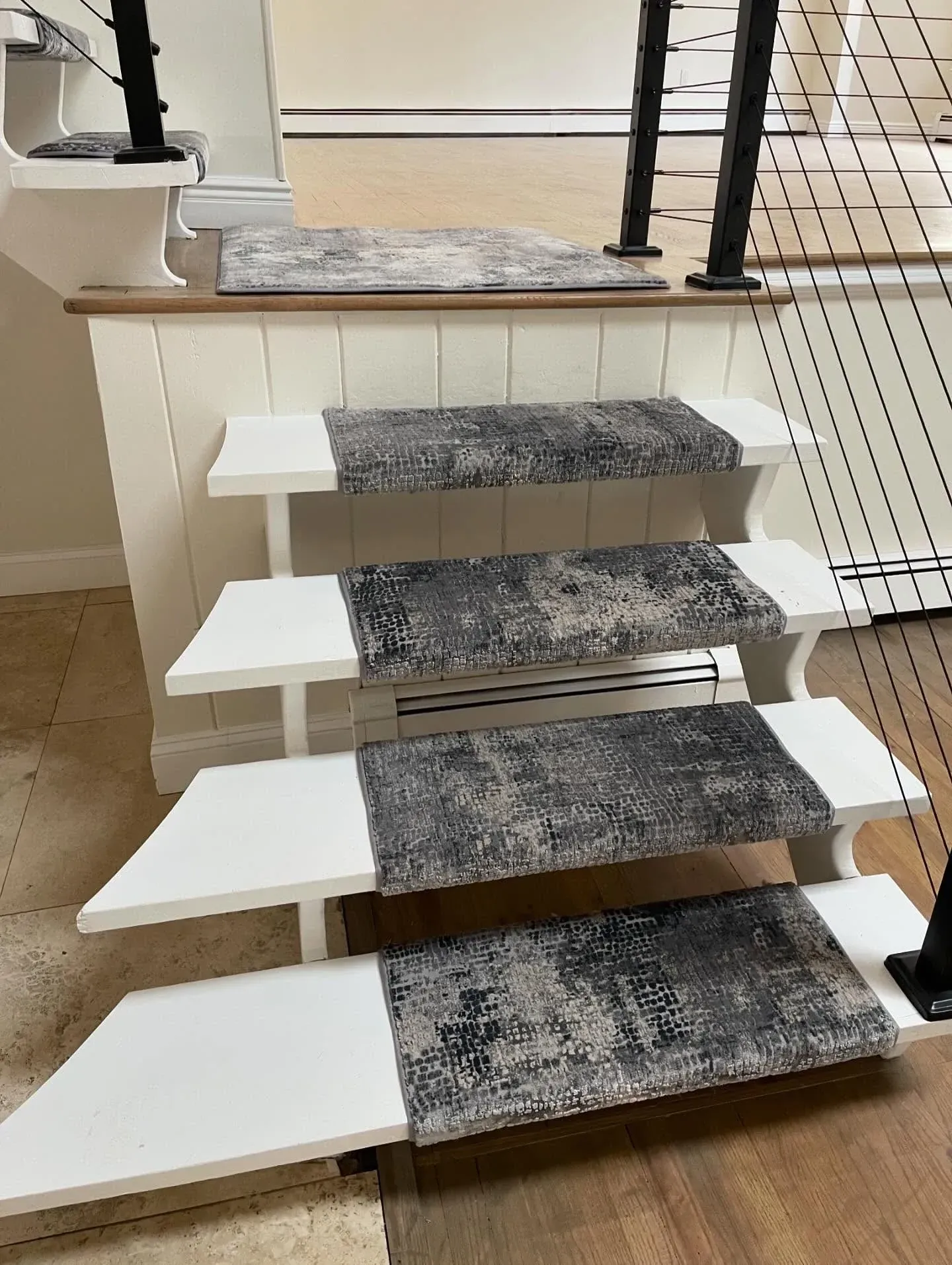 Floating staircase with white treads and gray carpet runners in a home interior