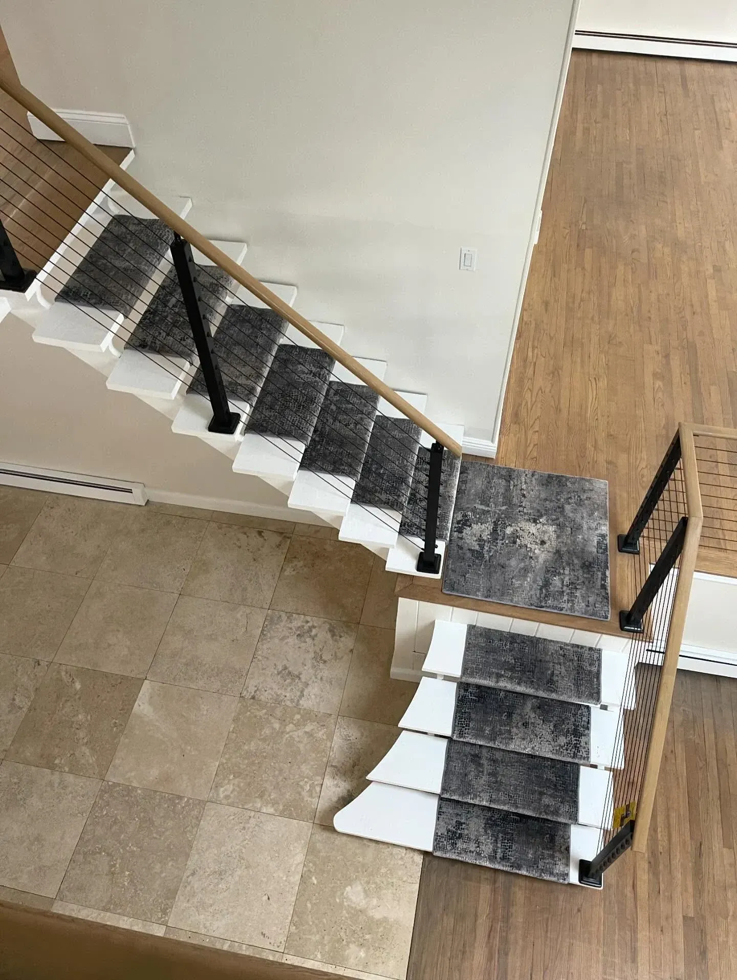 Staircase with gray carpet runner and wooden railing in a home interior