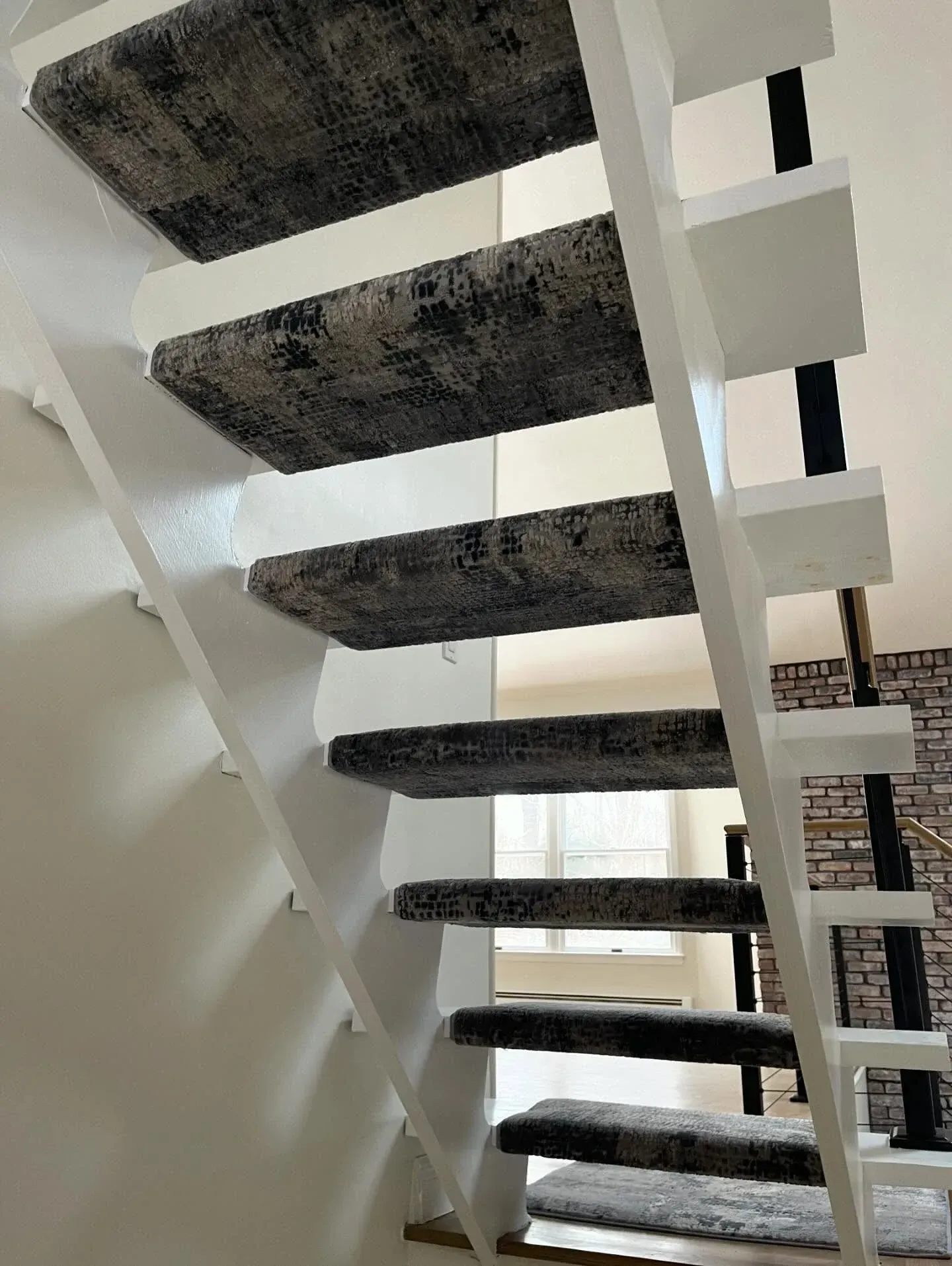 Staircase with gray carpeted steps and white railings, viewed from below.
