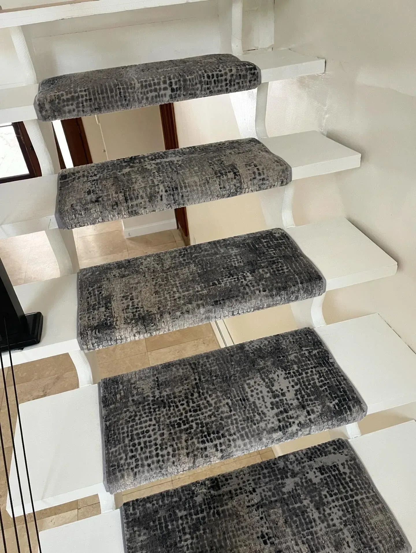 White staircase with dark gray carpeted treads viewed from above