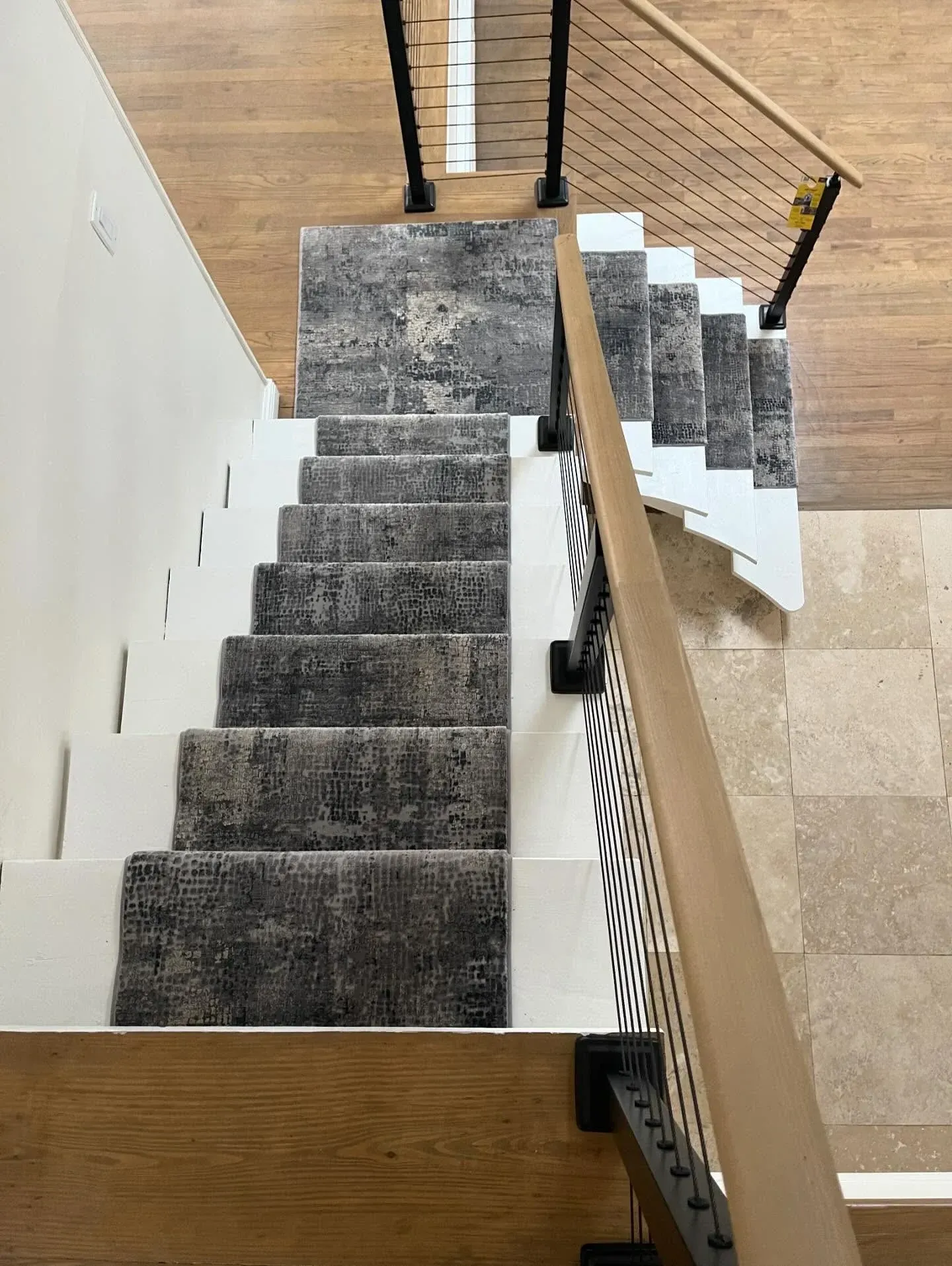 Carpeted staircase with wooden handrail descending to a brick-floored entryway.