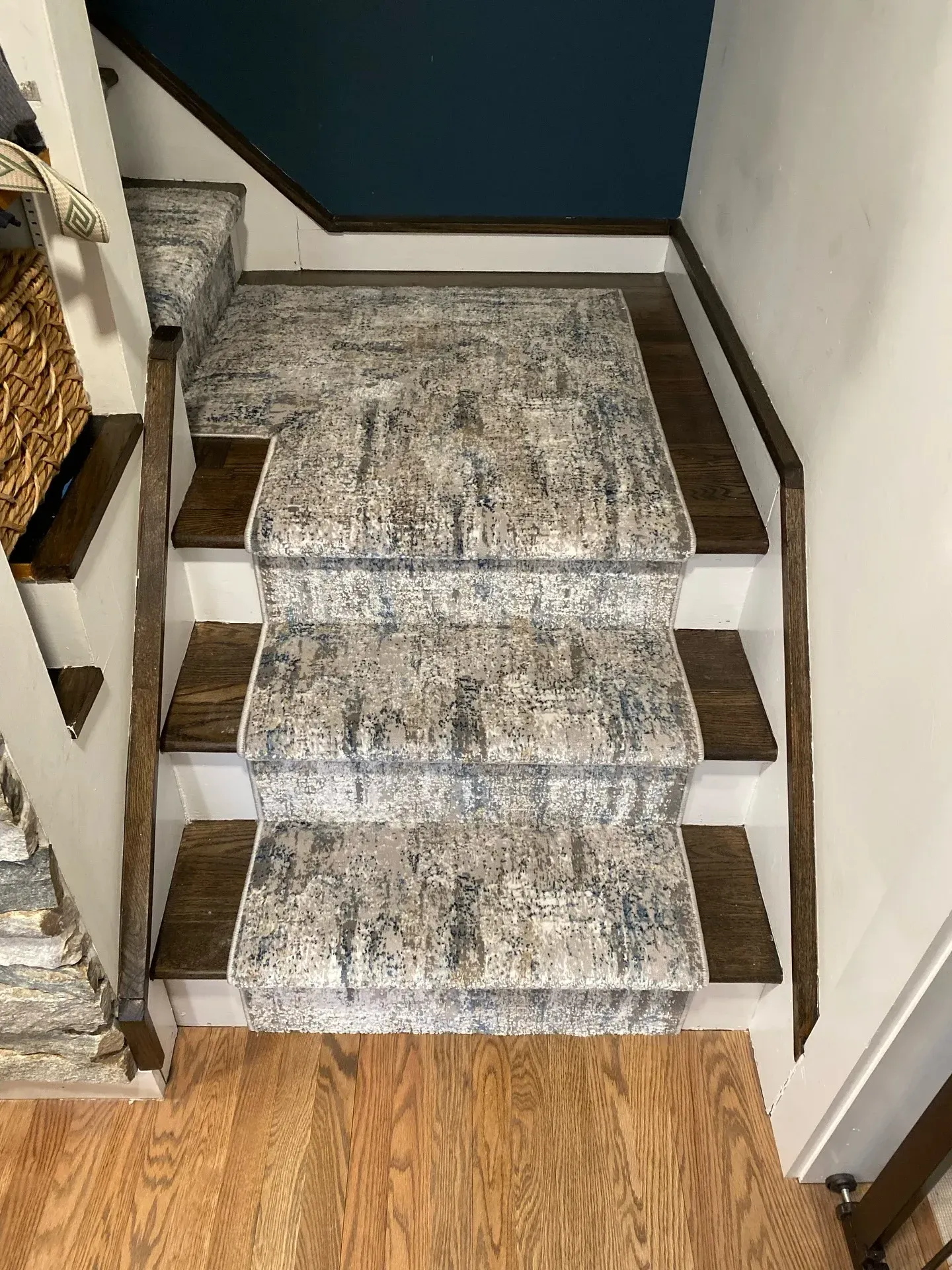 Carpeted staircase with three steps and wooden trim leading up from a wood floor