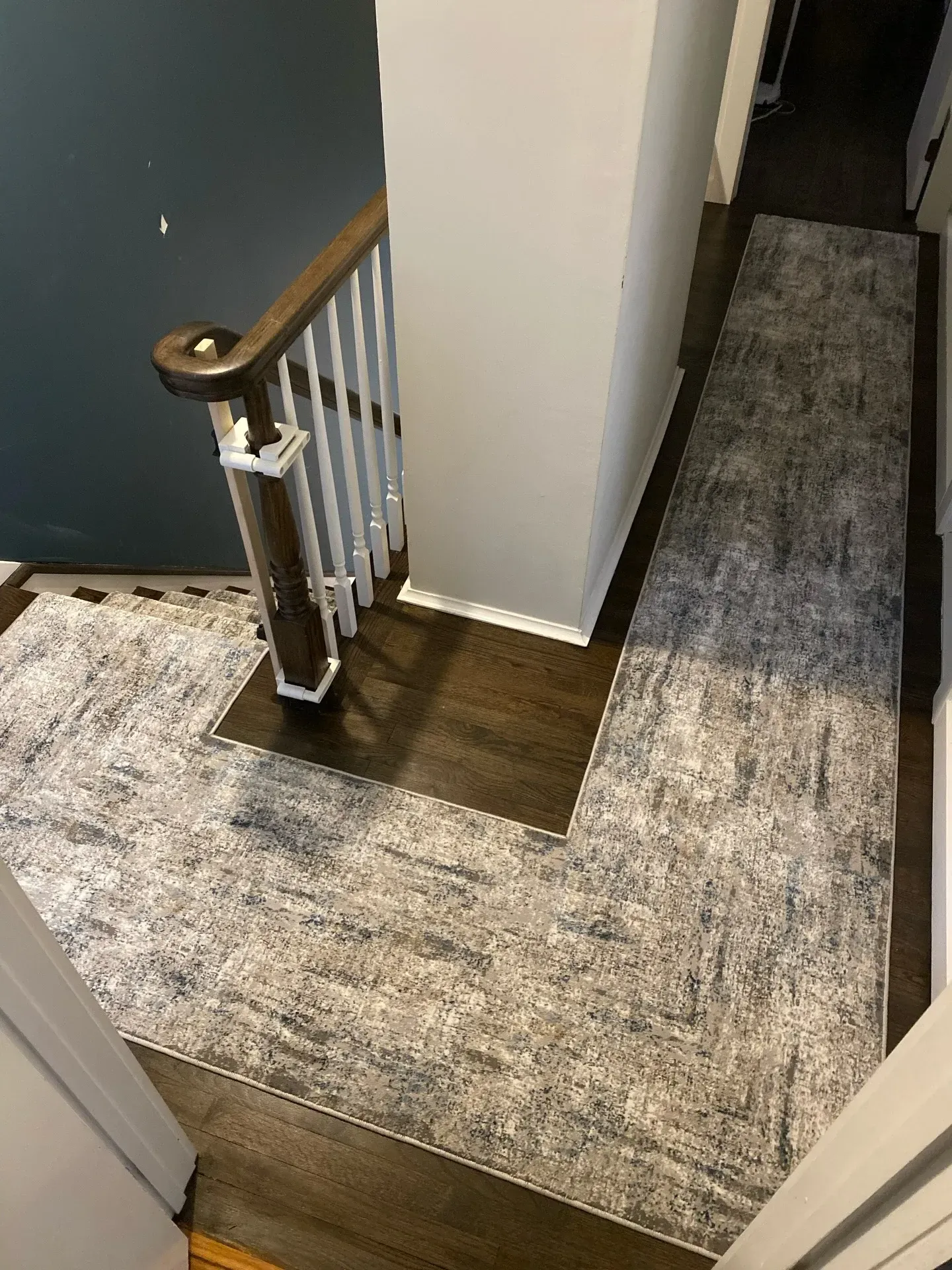 Hallway with carpet runner, wooden floor, and a staircase landing with white railing