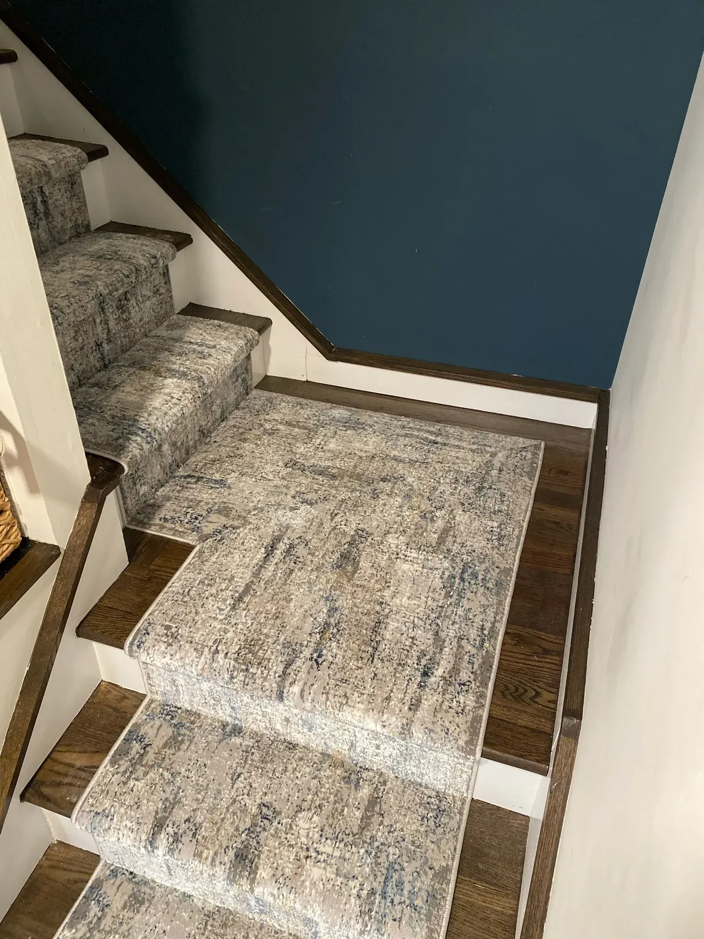 Carpeted stair landing with blue wall and patterned rug runner in a home hallway