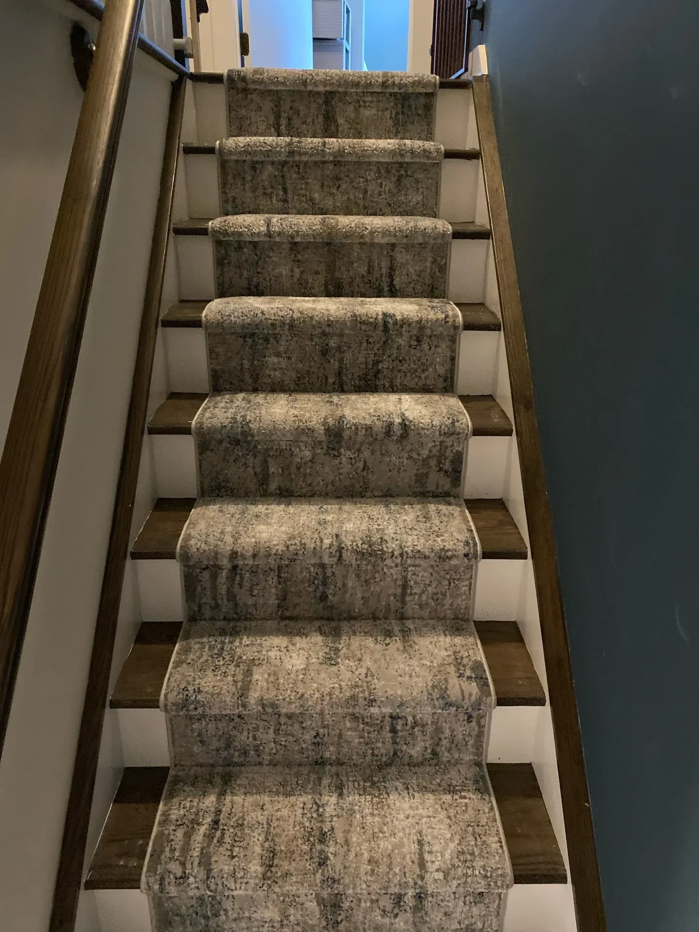 Carpeted staircase leading upward between dark walls with white trim.