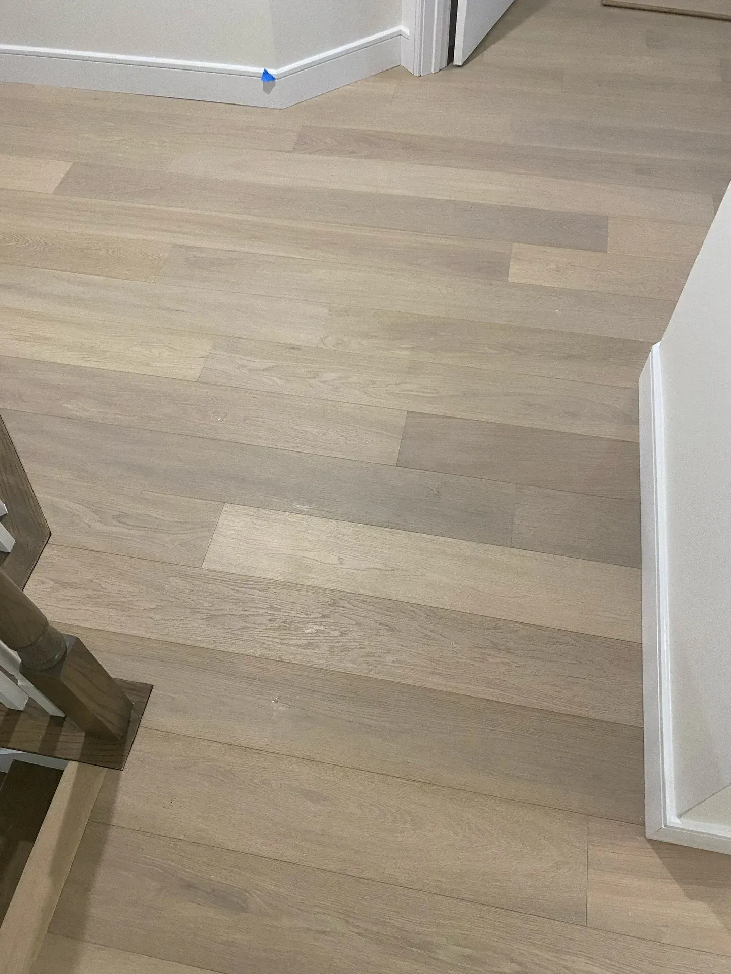 Light wood hallway floor with white walls and a doorway in the background.