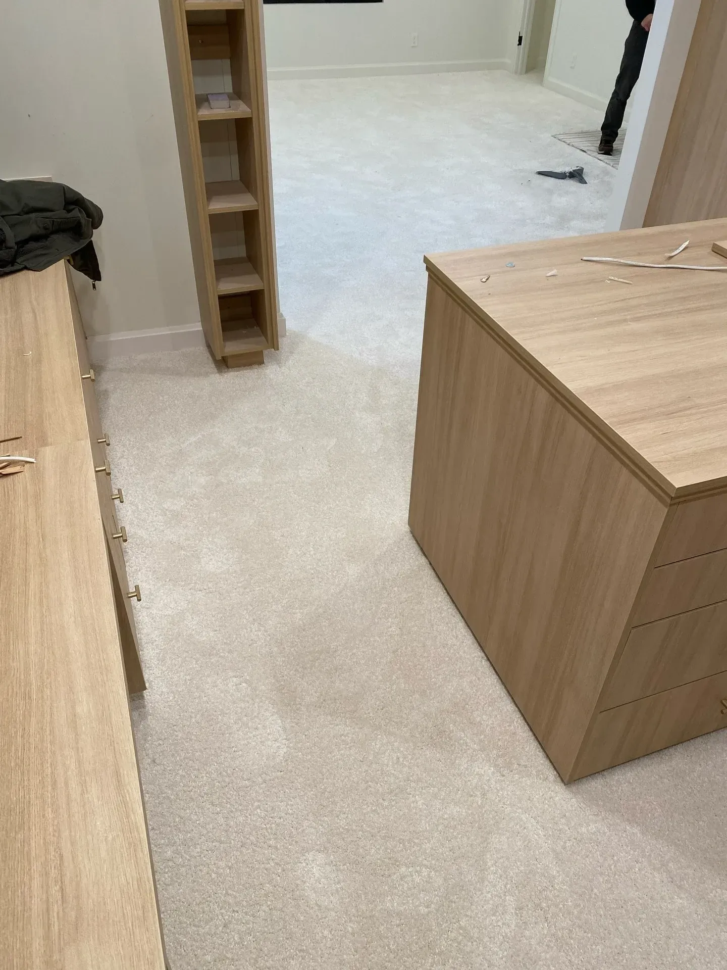 Unfinished room with carpet, a wooden shelving unit, and a large cardboard box on the floor.