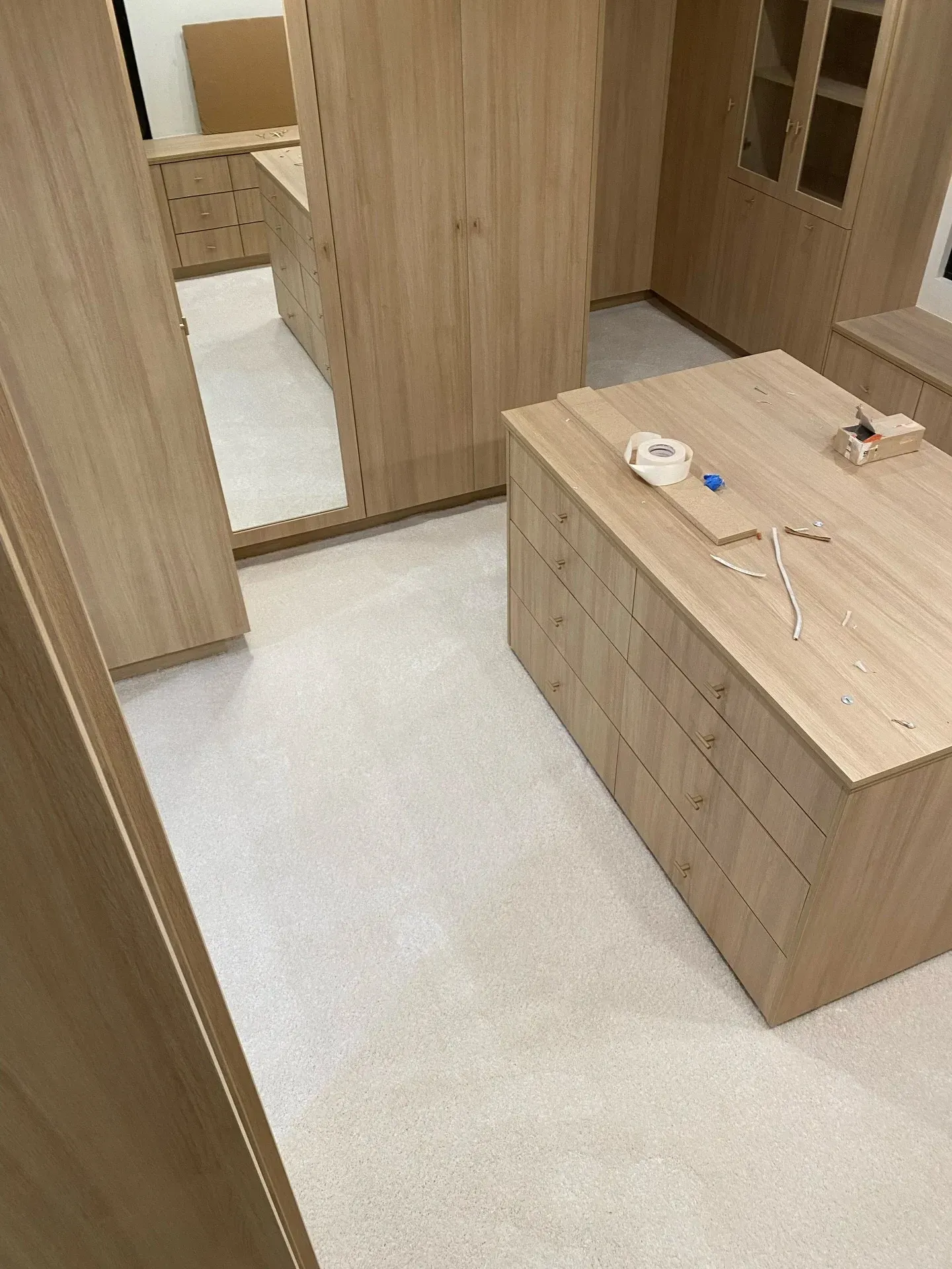 Wooden bedroom with a mirrored wardrobe and dresser on a light floor