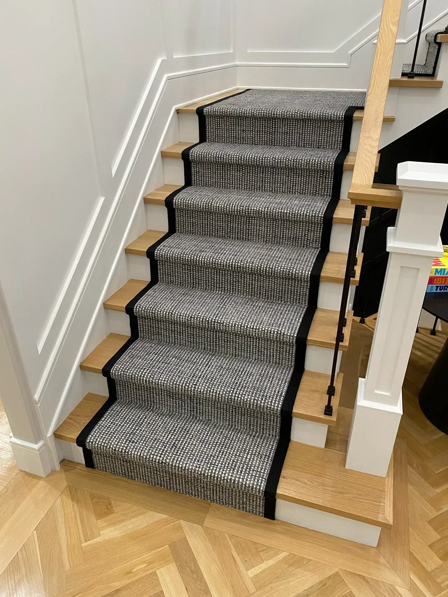 Carpeted staircase with black runner and wooden steps in a home interior.