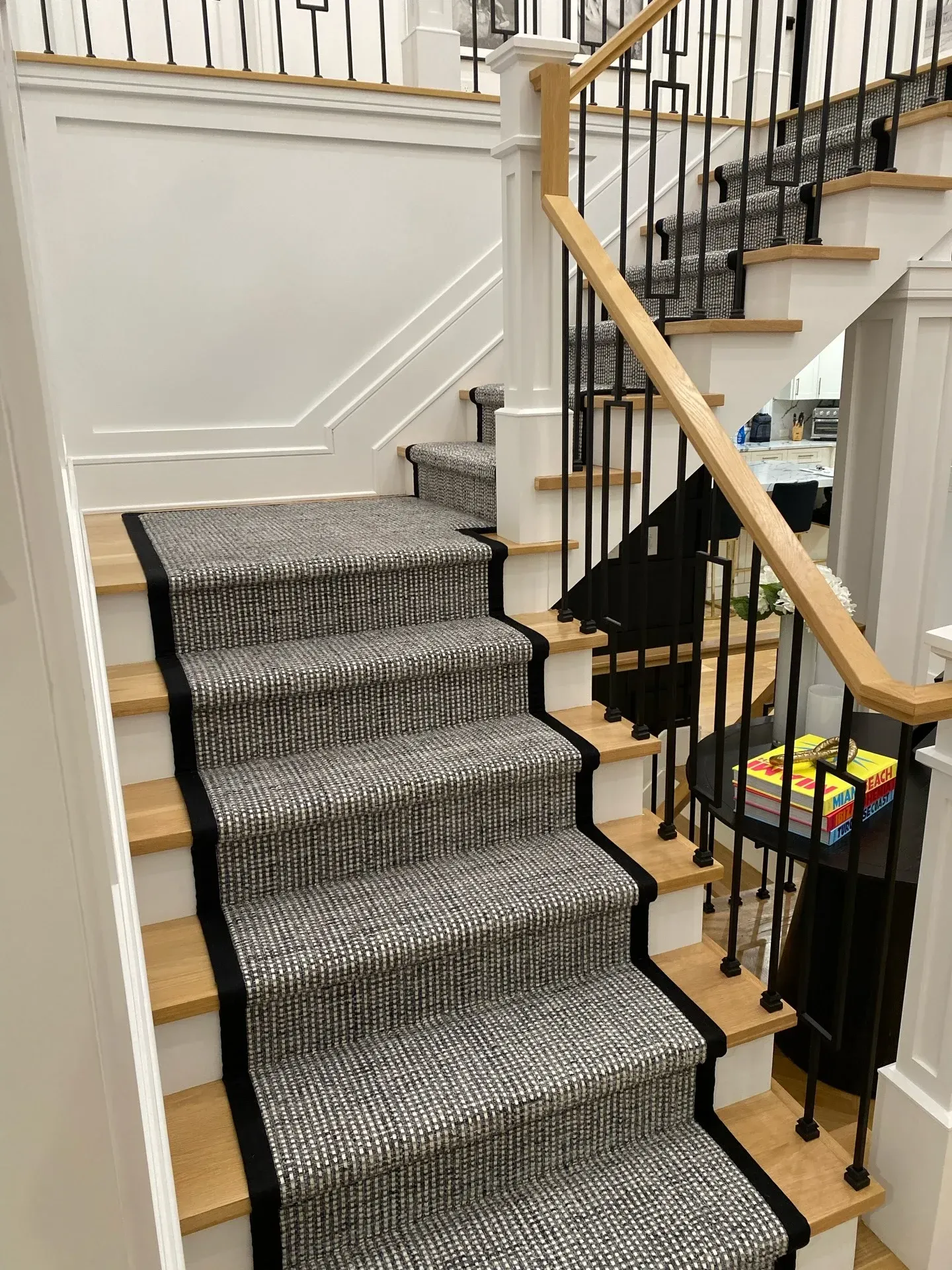 Carpeted staircase with black iron railing and light wood handrail in a home interior.