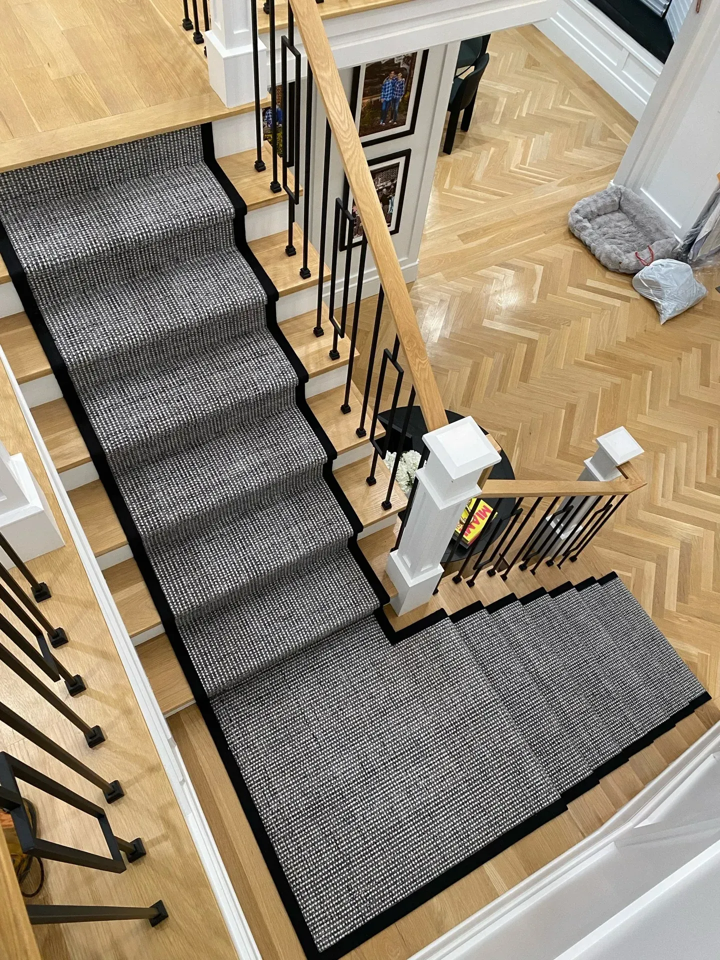 Staircase with dark carpet runner and black iron railing in a bright home interior.