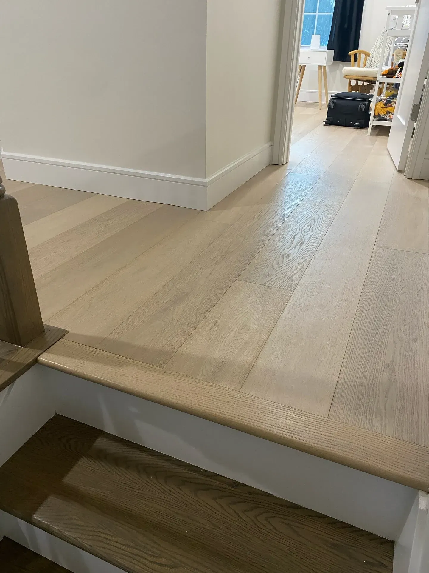 Interior hallway with a short step down to a light wood floor and a doorway into another room.