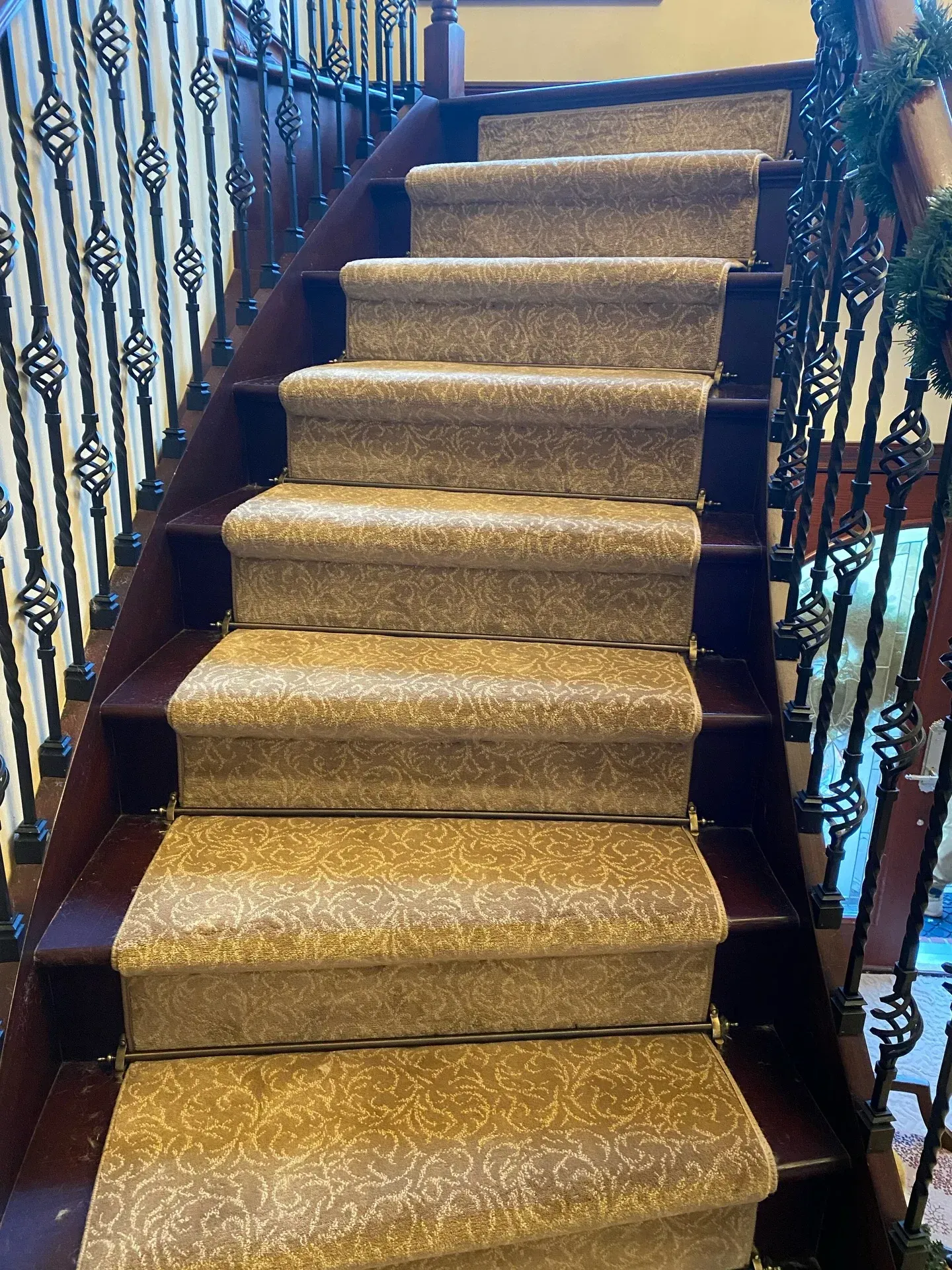 Carpeted staircase with ornate black railings and dark wood trim in a home interior