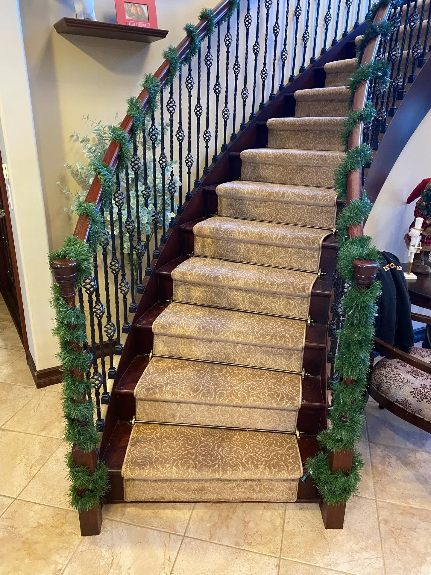 Decorated indoor staircase with gold-carpeted steps and green garland on the railing
