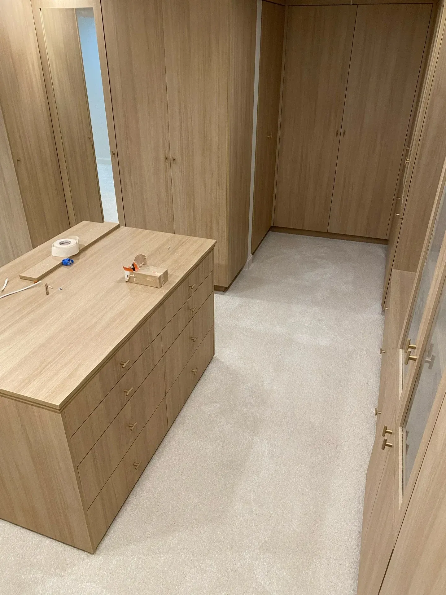 Wood-paneled walk-in closet with a dresser, mirror, and open hanging space.