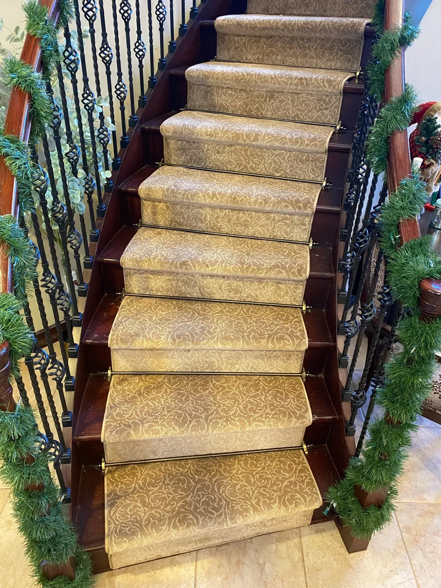 Carpeted staircase with gold runner and decorated railings indoors