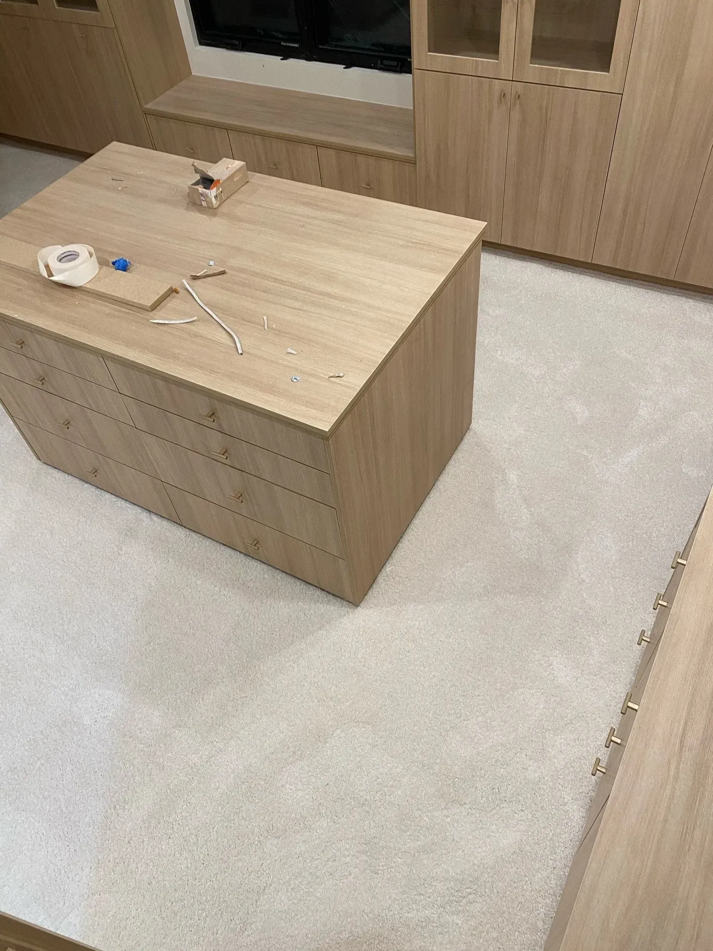 Small wooden room with a square table holding a few objects on a light carpeted floor.
