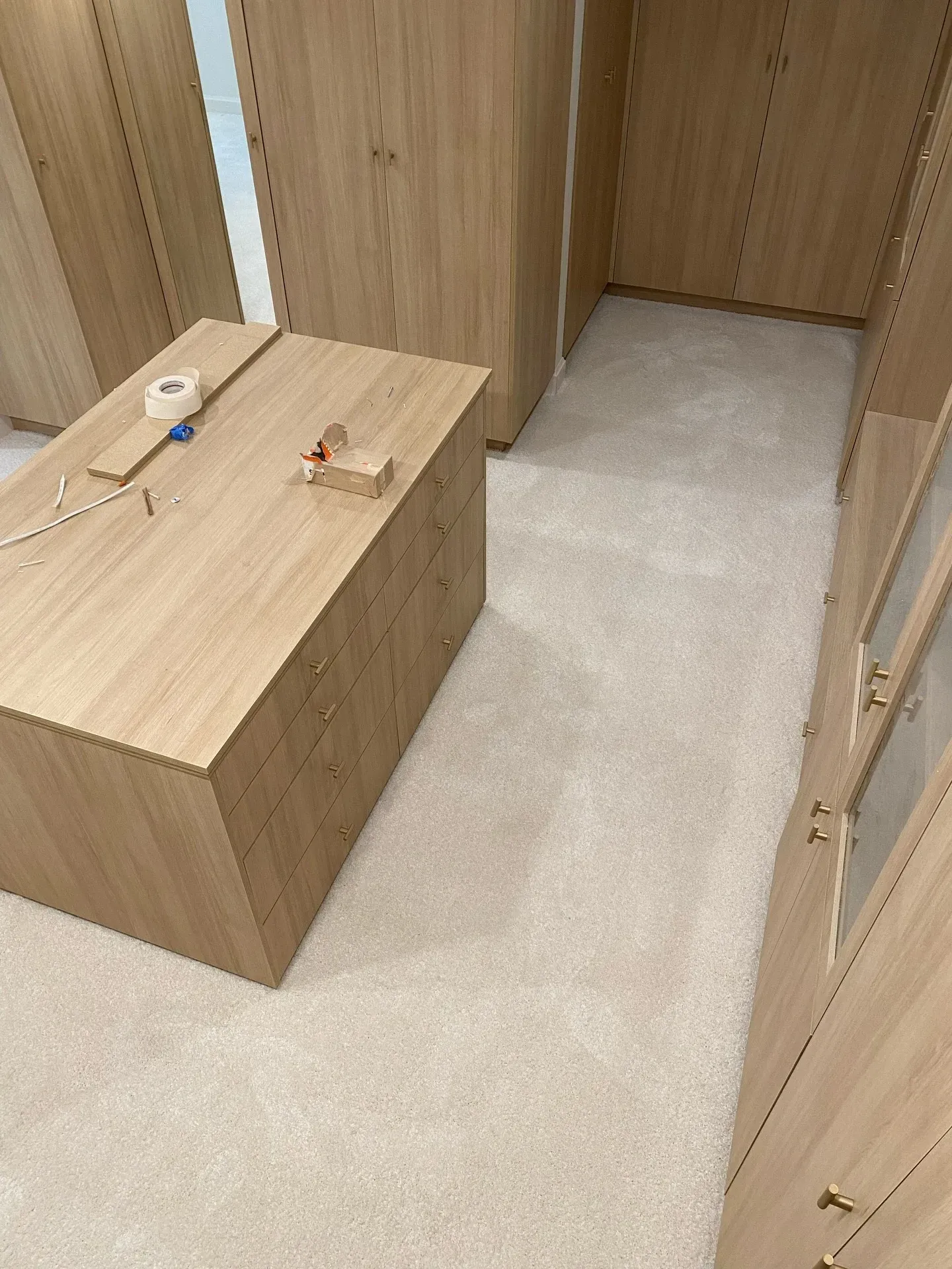 Wood-paneled hallway with beige carpet and a small wooden bench holding a few items.