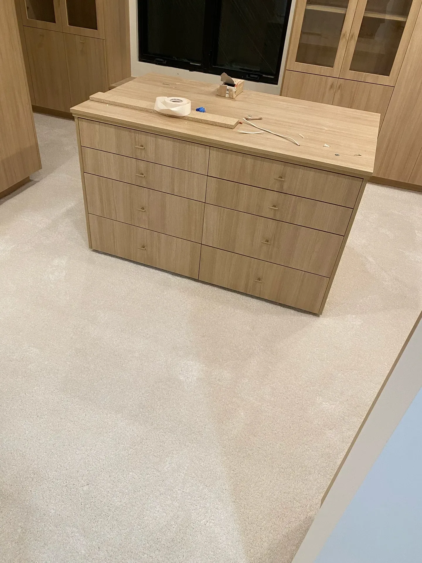 Wooden bathroom vanity with a light countertop and sink in a tiled restroom