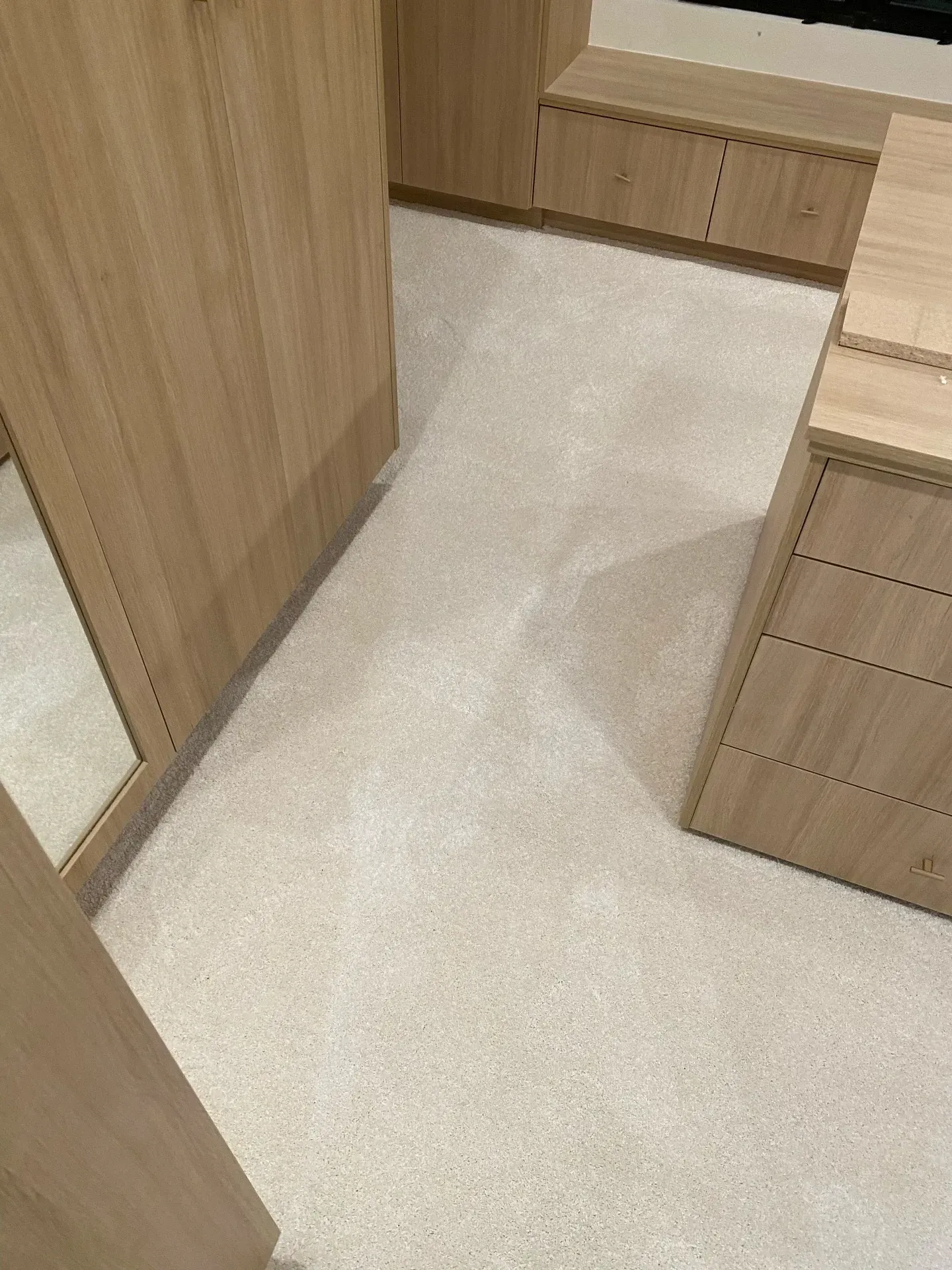 Light wood cabinets and a beige carpeted floor in a narrow interior hallway.