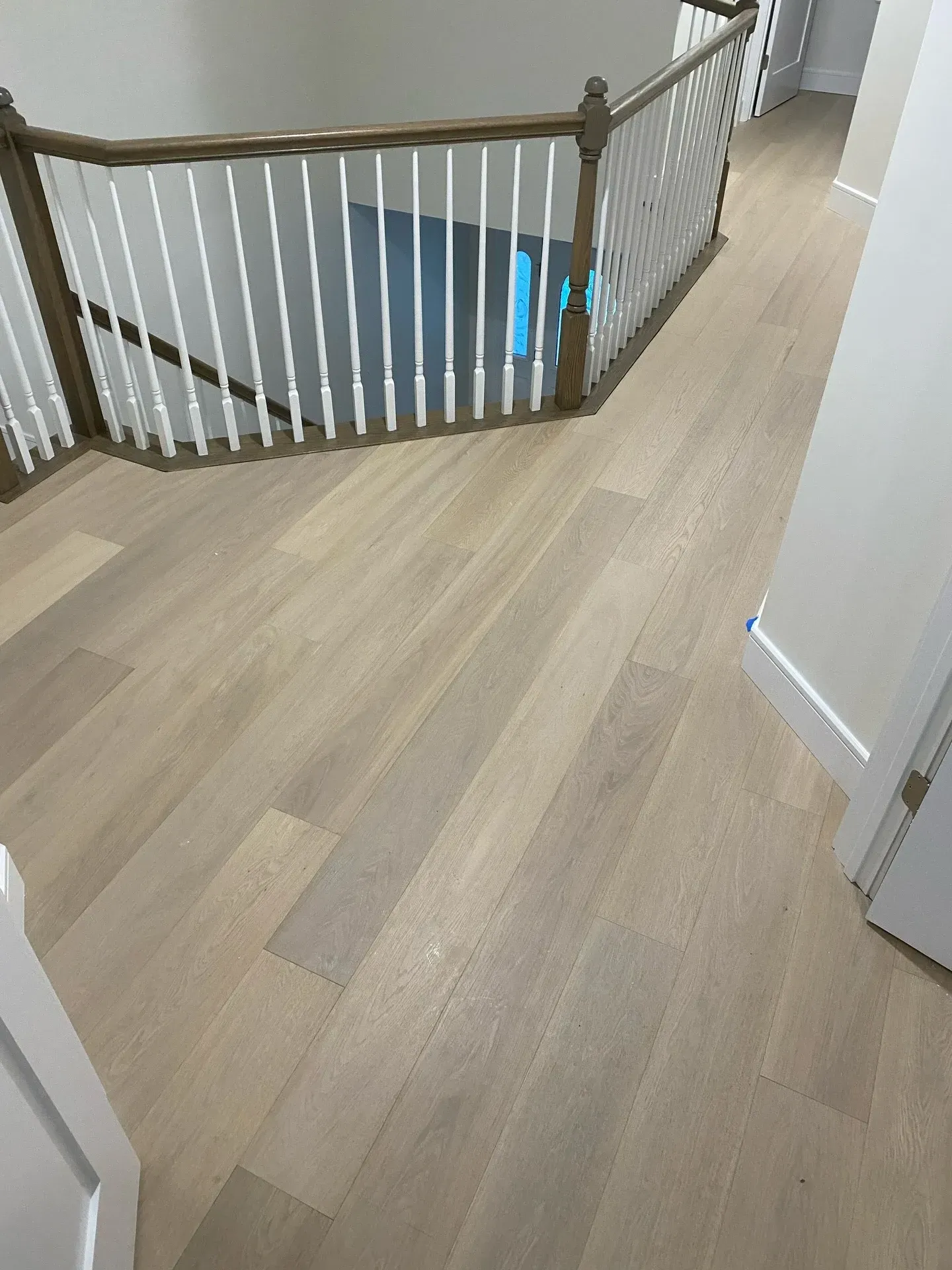 Light wood hallway with a curved staircase and white balusters near an open doorway