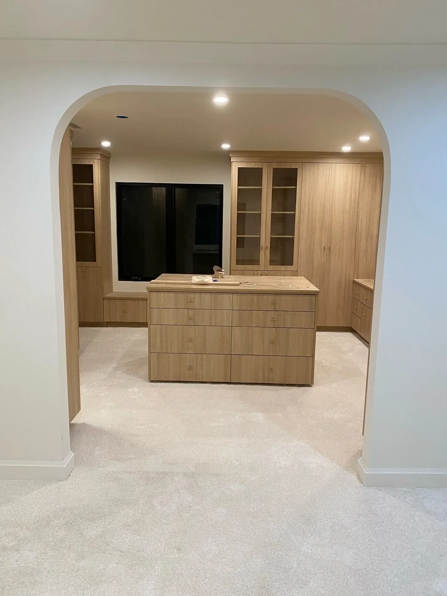 Wood-paneled kitchen with an island and arched doorway in a light-colored room