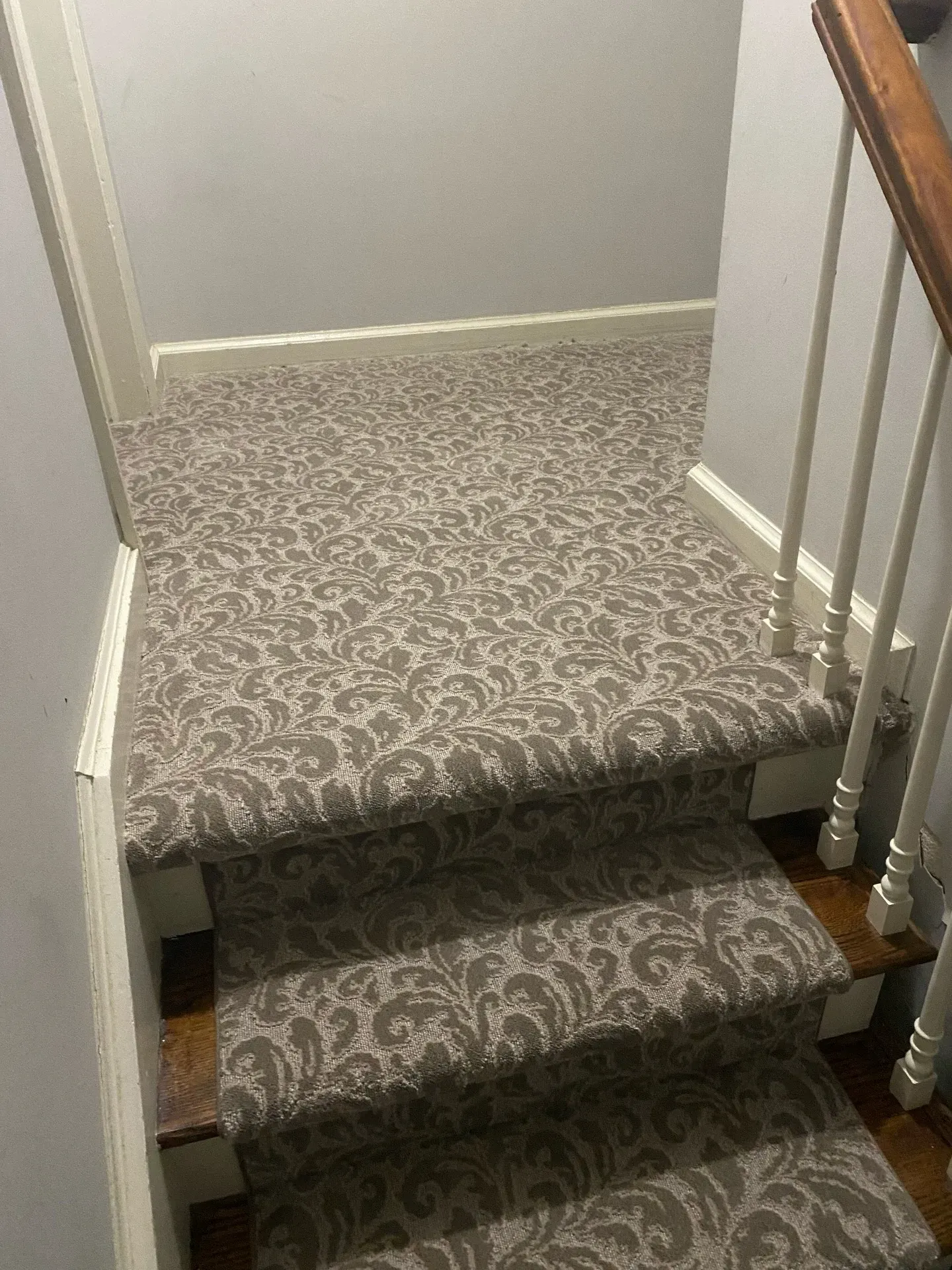 Carpeted indoor staircase with a small landing and white stair railings.